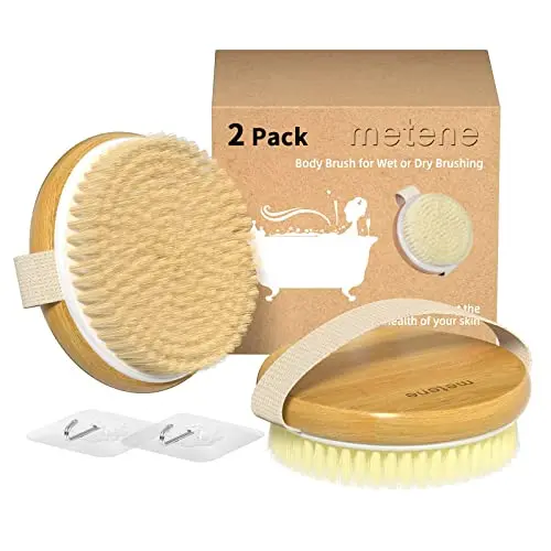 Two Metene bamboo body brushes with soft and stiff bristles on a wooden surface